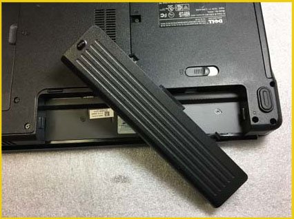 A laptop with its battery removed and placed on top, ready to be replaced.