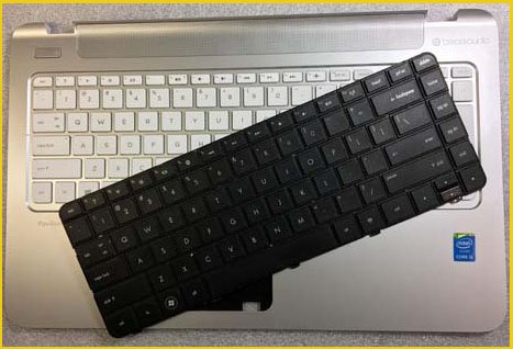 An image of a new laptop keyboard placed on top of a damaged keyboard, representing laptop keyboard replacement services offered by our repair shop in Flagler County.