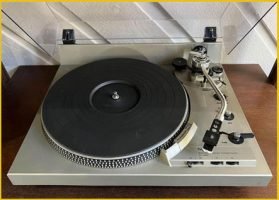 A close-up of a turntable, showing the tonearm, stylus, and various buttons and knobs.